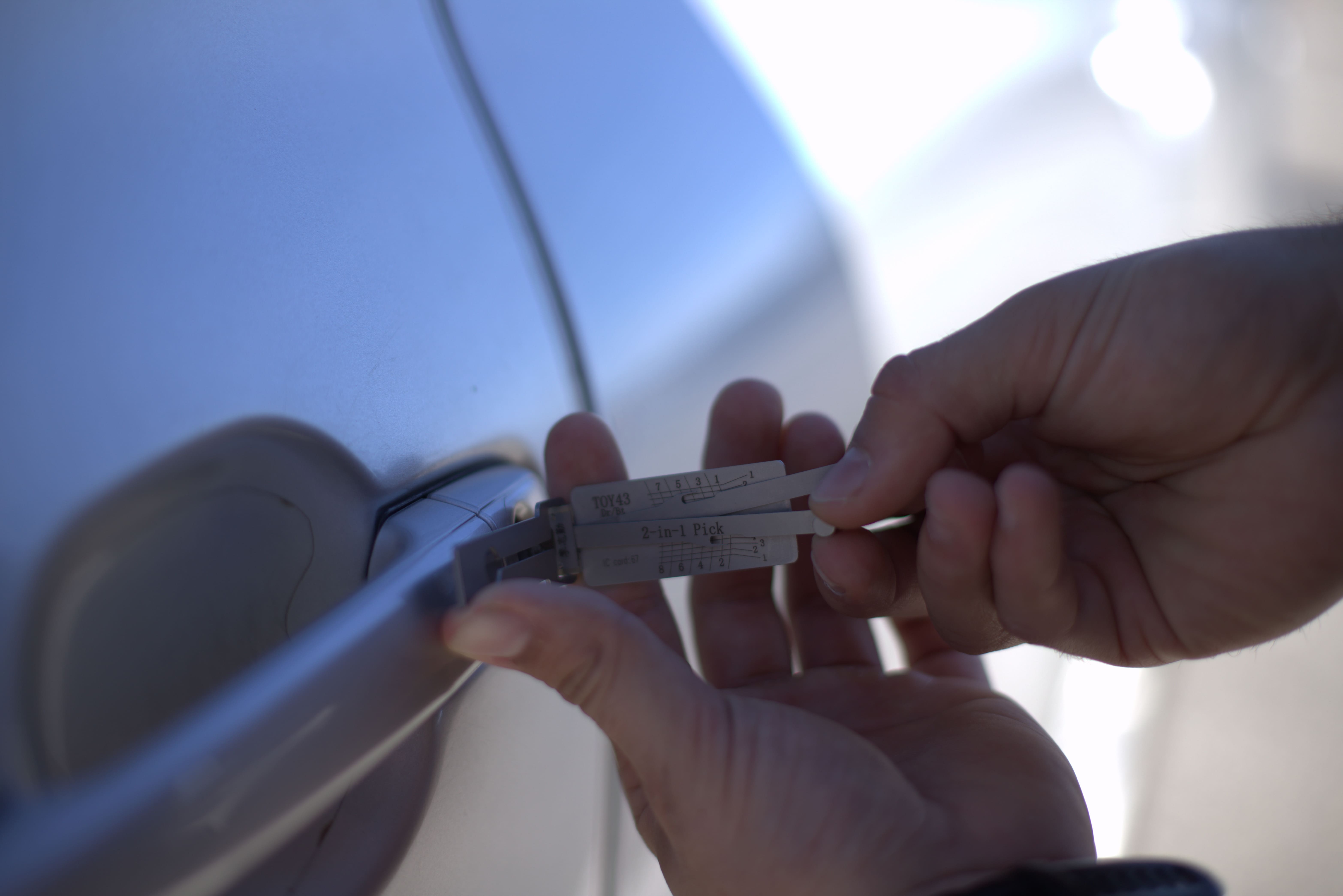 Expert locksmith using a lockpicking tool to unlock car door